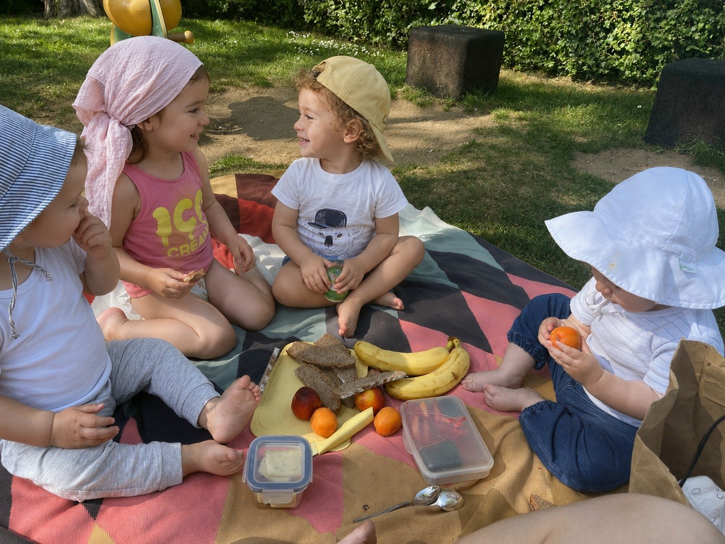 Kinder der Kindertagespflege Eisingen essen gemeinsam Brot, Obst und Käse auf einer Picknickdecke